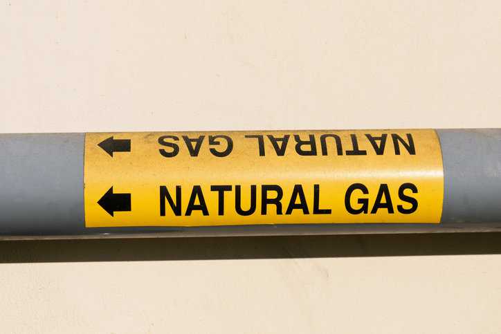 Natural gas pipe marked with yellow labeling and arrow in accordance with ASME A17.1-2023 legend.