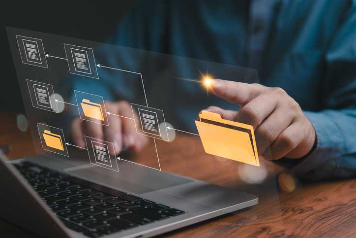 Man working on computer sorting electronic records with finger as part of information management process.