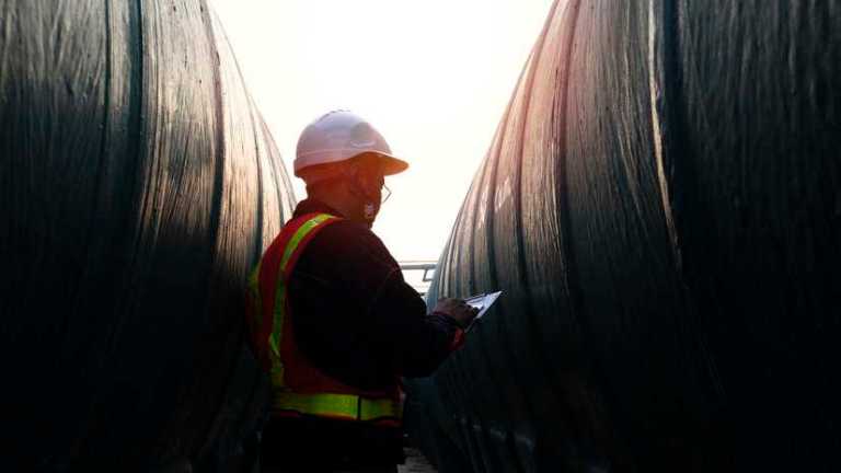 Engineer at factory under sunset, conducting conformity assessment in practice.