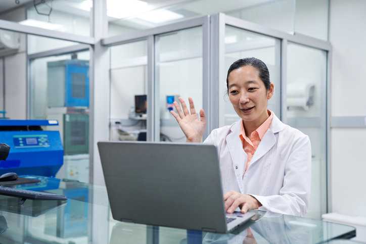 Lab technician getting on video call in laboratory for remote assessment to begin.