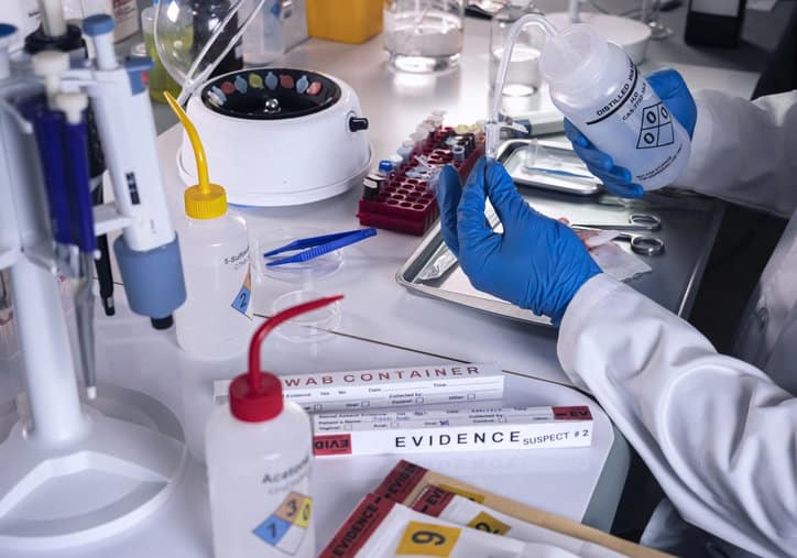 Police scientist extracts rapid DNA sample in a forensics lab adhering to the Rapid DNA Act of 2017.