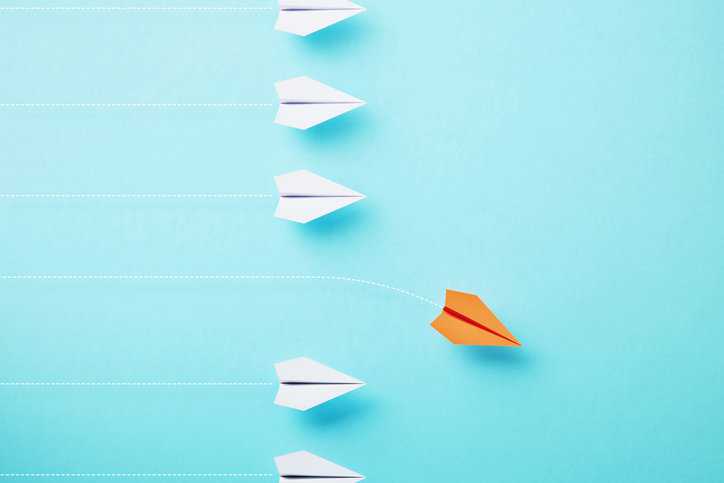 Orange paper plane sinking over blue background, representing the nonconformity needing corrective action.