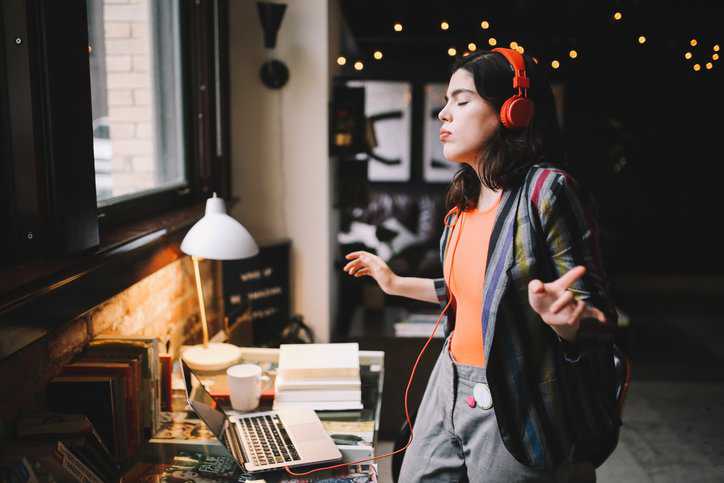 A woman listening to music in her earphones that adhere to acoustical testing in ANSI ASA S3.7-2016 (R2020).
