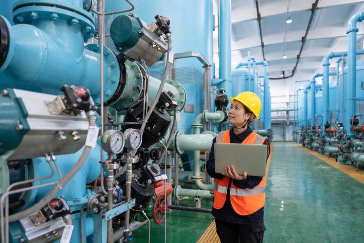 A female engineer works in a chemical nuclear power plant that adheres to ANSI/ANS-20.2-2023 nuclear safety design criteria.