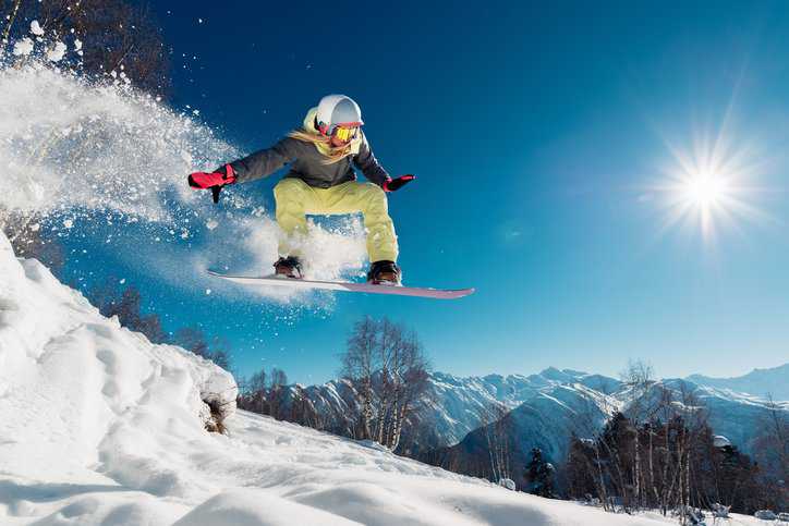 Athlete jumping with snowboarding on a snowy mountain in the winter with her bindings adhering to ISO 10958-1:1998  and ISO 10958-2:2015.