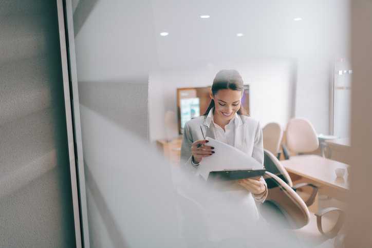Competent female worker reviewing the standard document needed to achieve certification.