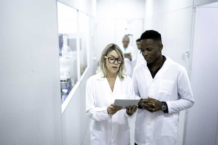 Technicians discussing lab results while walking through laboratory.