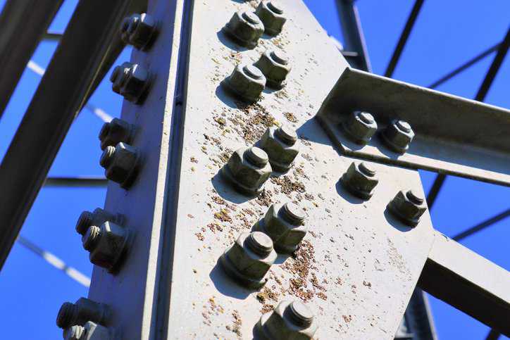 Close up view on a big power transmission tower transporting electricity with steel tower bolts that adhere to ASTM A394-08(2024).