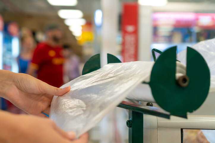 Close-up of women's hands tearing off a sustainable biodegradable plastic bag that adheres to ASTM D6954-24.