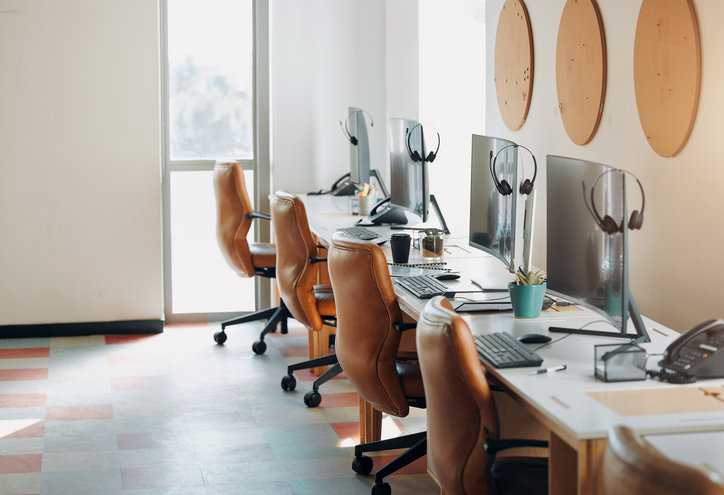 Desktops set up in cool start up business environment with leather chairs.