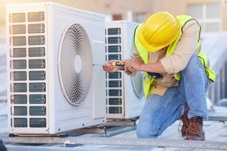 Air conditioning technician on roof for hvac repair that adheres to ANSI/ASHRAE 193-2010 (R2024).