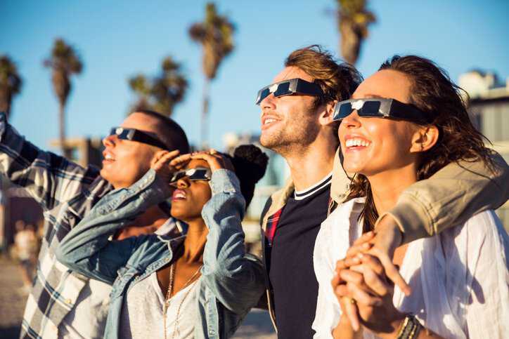 Friends watching the solar eclipse wearing protective eye glasses that adhere to ISO 12312-2:2015.