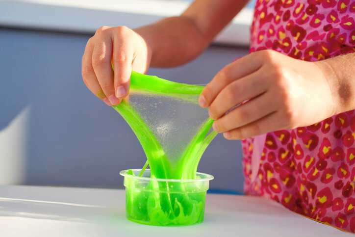Close up of a child playing with green slime that adheres to microbiological testing for toys in ISO 8124-12:2023.