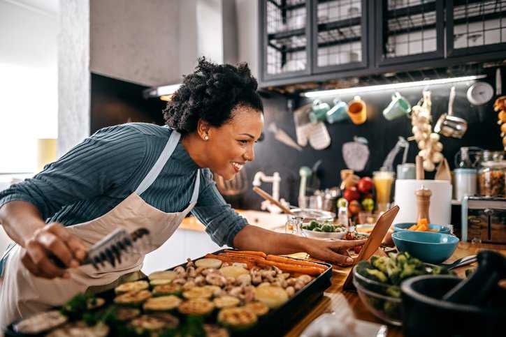 Woman in her domestic kitchen grilling food on an electrical barbecue that adheres to IEC 60335-2-9:2019.