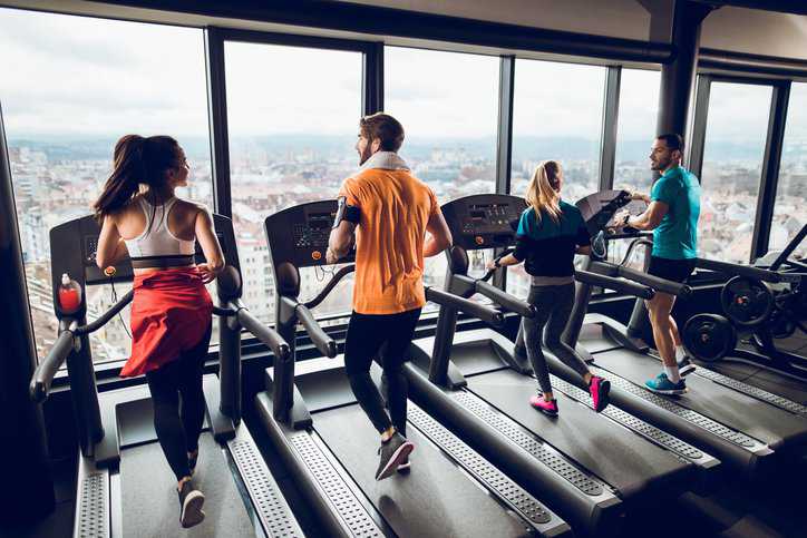 Rear view of people doing cardio on treadmills in a gym that adhere to ASTM F2115-19.
