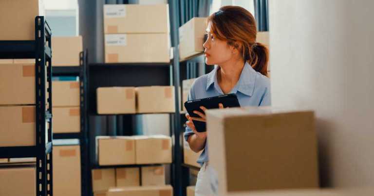 Businesswoman assessing boxes in warehouse.