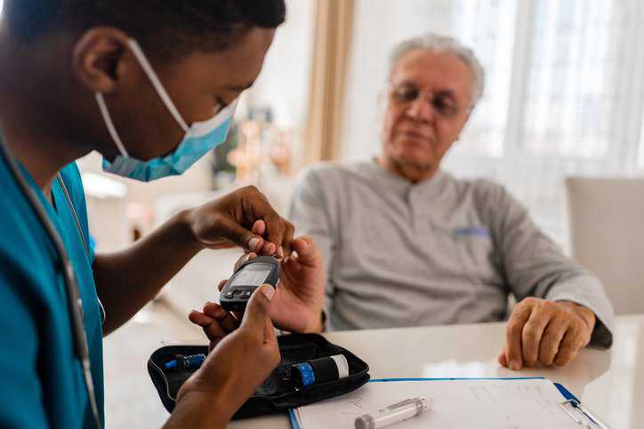 Nurse checking the health of his patient with diabetes to assure the patient's blood-glucose monitoring system is adhering to ISO 15197:2013.