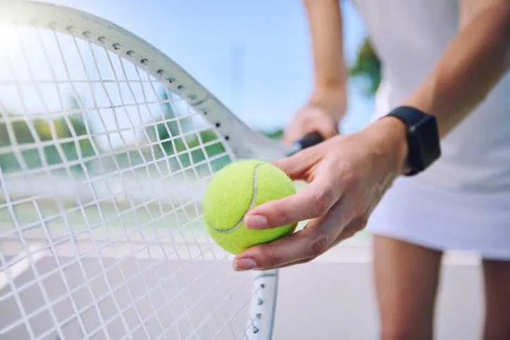 Professional athlete holding a tennis racket, adhering to ISO 11416: 1995, and tennis ball to make a serve.