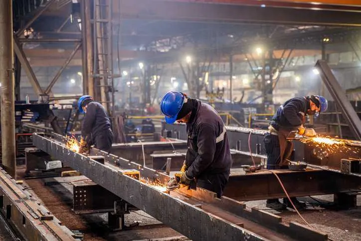 Metal workers using a grinder that adheres to ANSI/ASSP Z9.6-2018.