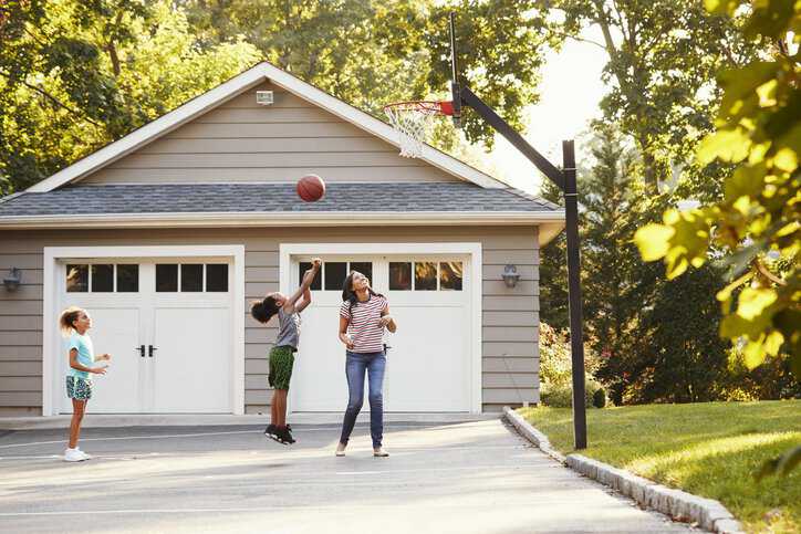 Family playing basketball at their home with a basketball system adhering to ASTM F1882-15.