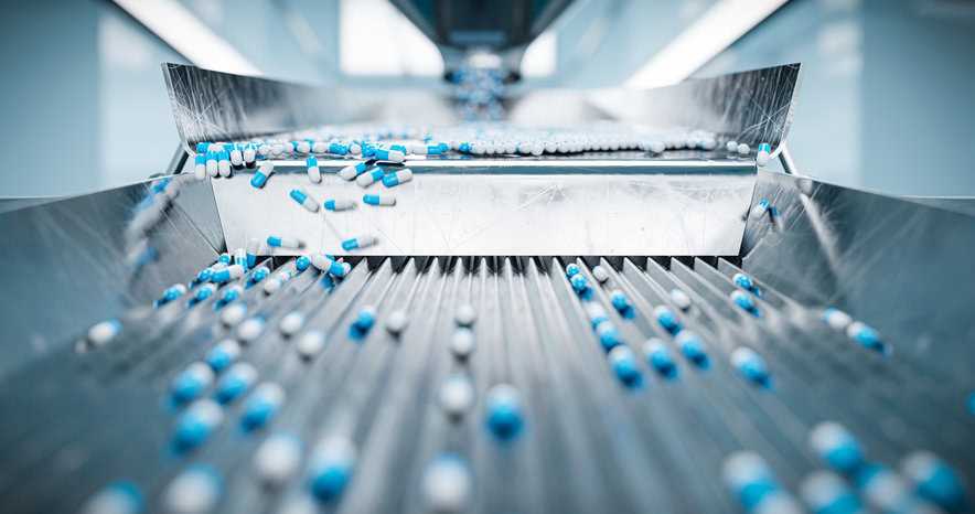 Blue and white pharmaceutical tablets being sorted by machine.