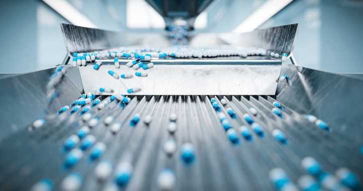 Blue and white pharmaceutical tablets being sorted by machine.