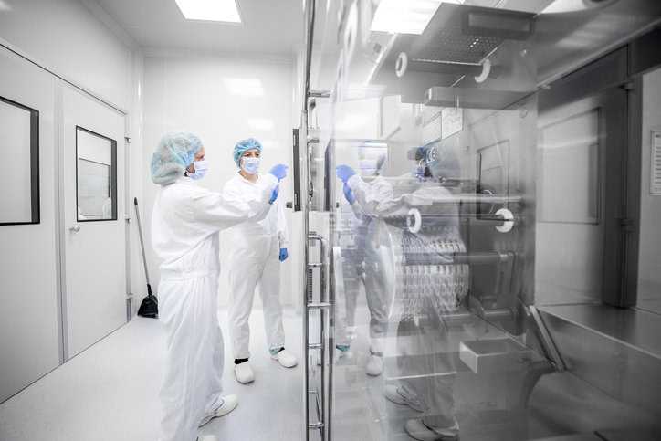 Two lab technicians fully covered in a cleanroom