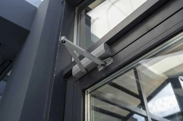A close up of door closer and door pivot on a commercial building's door that adheres to ANSI/BHMA A156.4-2024.