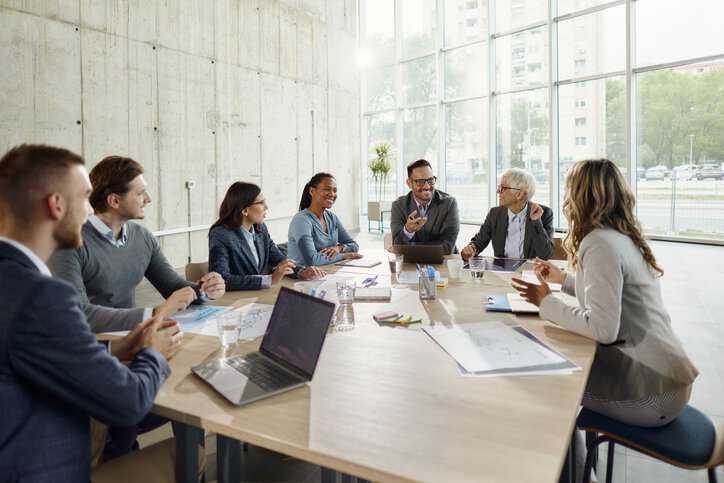 Large group of happy standards professionals communicating while working on standards development, while adhering to IWA 30-1:2019 and IWA 30-2:2019.