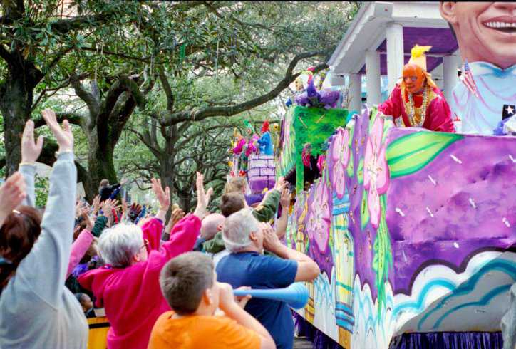 Large, colorful parade float, adhering to ANSI E1.57 – 2016 (R2021), with bystanders celebrating Mardi Gras.