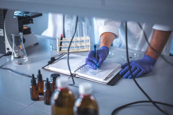 Scientist writing RM documentation in lab.