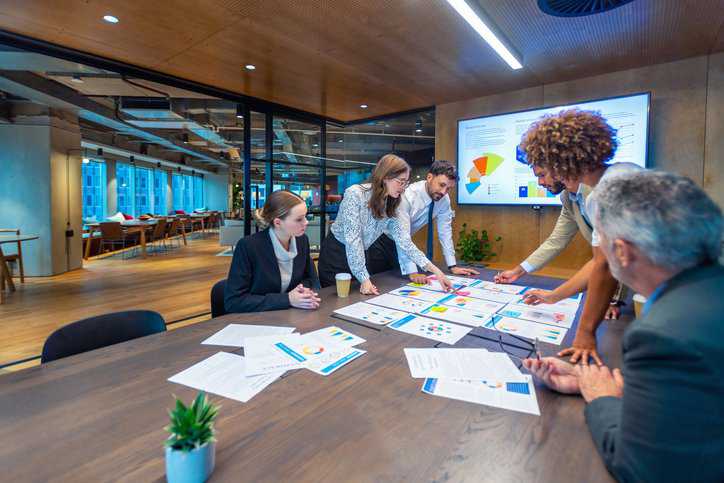 Employees in an organization overlooking financial data and assets to adhere to ISO 55000:2024 asset management requirements.