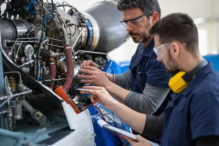 Two engineers working on helicopter with suspect counterfeit EEE parts in hanger.