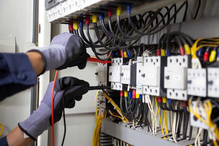Electrician engineer tests electrical installations and wires on relay protection system to assure that the electrical equipment is in compliance with ANSI/NETA ECS-2024.