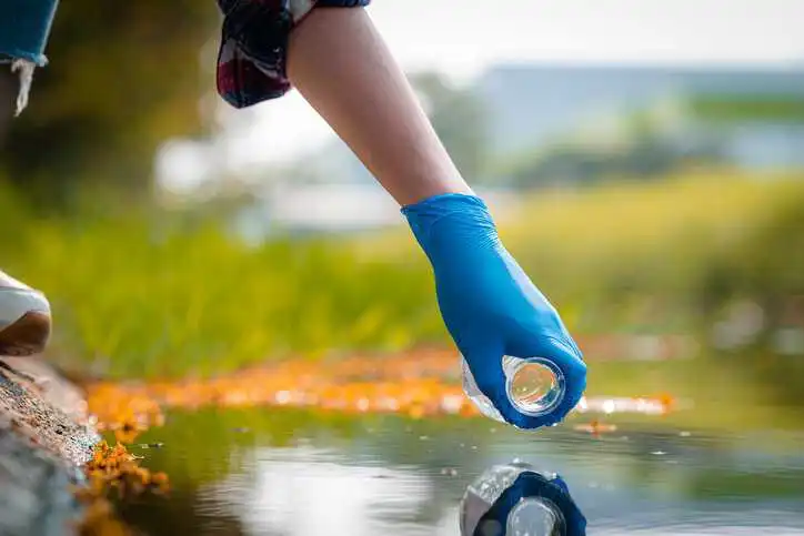 Hands of scientists collecting water samples for analysis and research on water quality, adhering to the ANSI/ASCE/EWRI 33-23 framework.