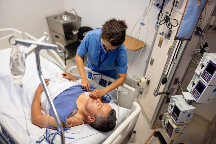 Nurse placing electrodes on a patient at the hospital with an implantable neurostimulator that adheres to ANSI/AAMI/ISO 14708-3:2017.