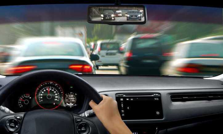 Driver in a motor vehicle on a road with lots of traffic, adhering to ANSI/ASSP Z15.1-2024 and ISO 39001:2012 road safety guidelines.