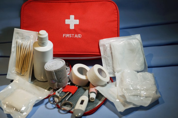 Contents of a workplace first aid kit compliant with ANSI/ISEA Z308.1, including bandages, trauma pads, scissors, antiseptics, gloves, and a burn dressing.