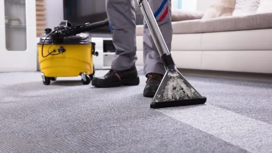 Person cleaning textile floor coverings (i.e., carpets) in a residential home that adheres to ANSI/IICRC S100-2021 procedures.