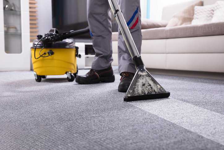 Person cleaning textile floor coverings (i.e., carpets) in a residential home that adheres to ANSI/IICRC S100-2021 procedures.