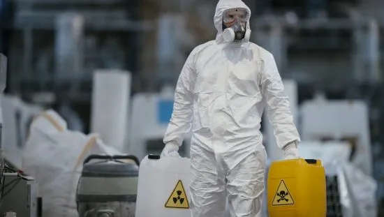 Factory worker working with dangerous chemicals and contaminants, so he is wearing protective coveralls that adhere to ANSI/ISEA 101-2014.