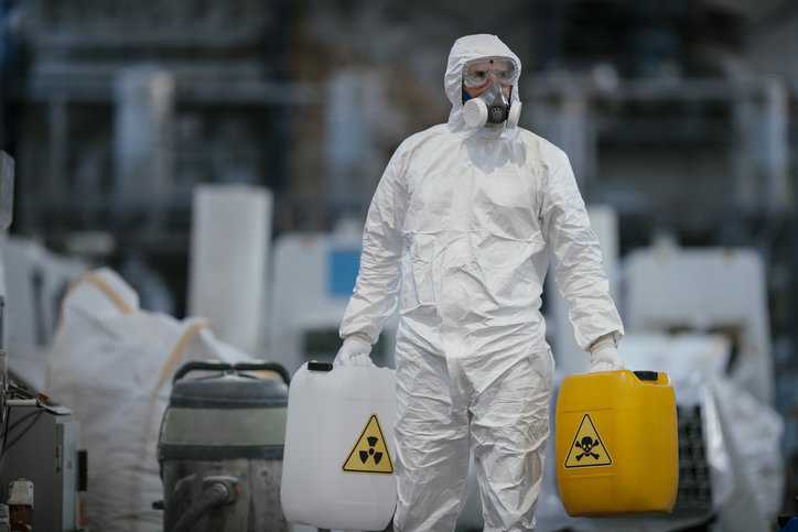 Factory worker working with dangerous chemicals and contaminants, so he is wearing protective coveralls that adhere to ANSI/ISEA 101-2014.