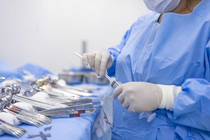 Health care doctor sterilizing and disinfecting medical devices for surgery while adhering to ANSI/AAMI ST58:2024 practices.