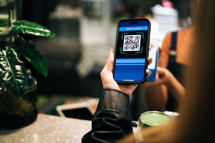 Customer scanning a QR code to pay for his matcha at coffee shop. The QR code contains alignment patterns that comply to ISO/IEC 18004:2024.