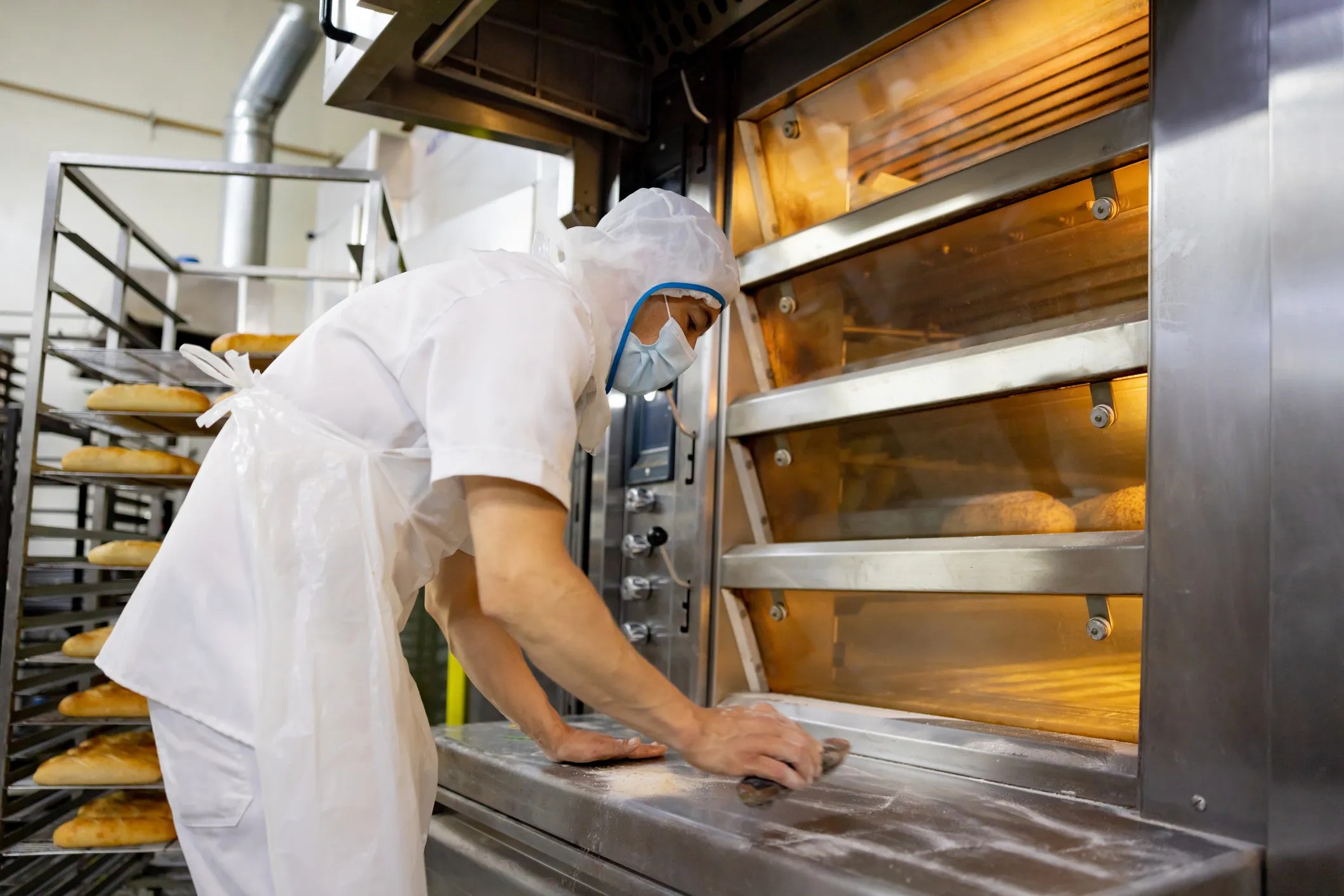 A person cleaning commercial kitchen equipment with sanitizer to maintain hygiene and food safety standards like NSF/ANSI 4-2025.