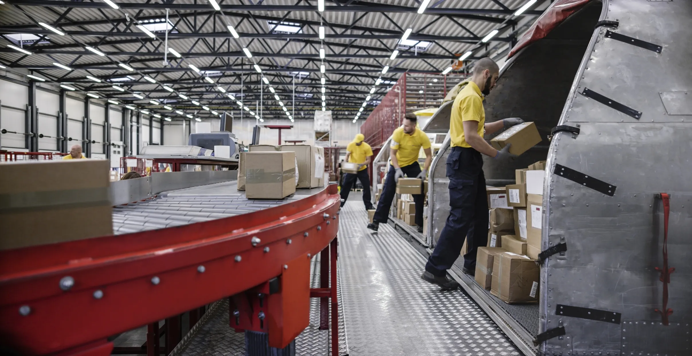 Workers loading boxes onto red ergonomic conveyor.