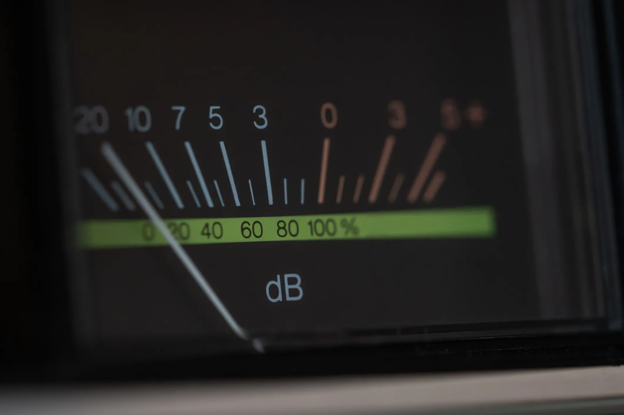Close-up of an analog decibel meter showing sound levels, with a needle indicating the current dB value that adheres to ASA/ANSI S12.12-1992 (2024) sound power level requirements.