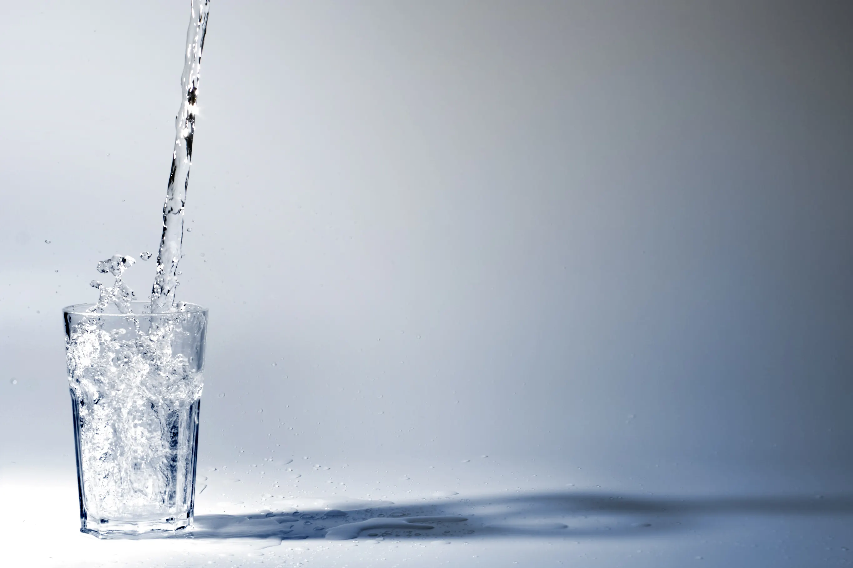 Glass of water being filled with water that follows ANSI 61-2022.