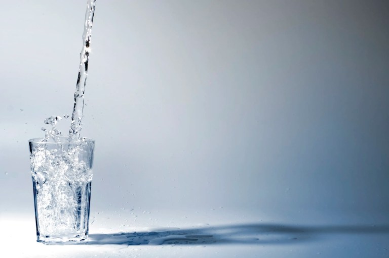 Glass of water being filled with water that follows ANSI 61-2022.