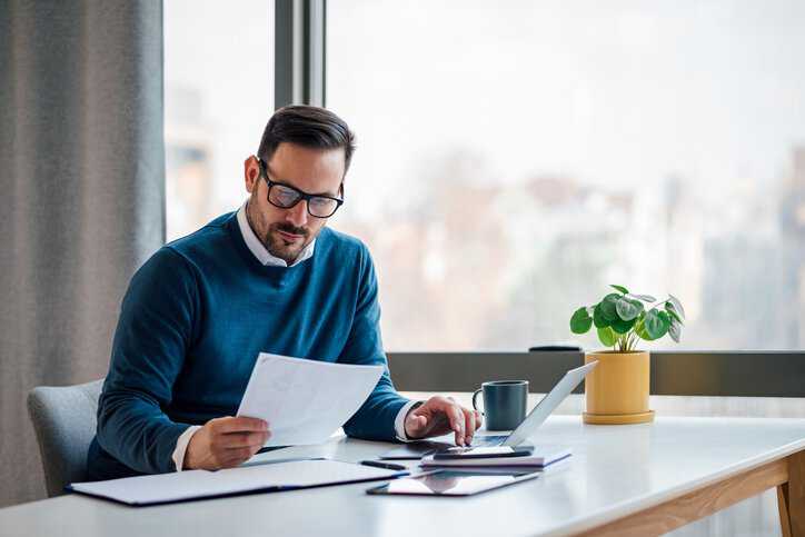 Businessman checking cyber insurance for his cyber security company, assuring it adheres to INCITS/ISO/IEC 27102:2019 (2020).